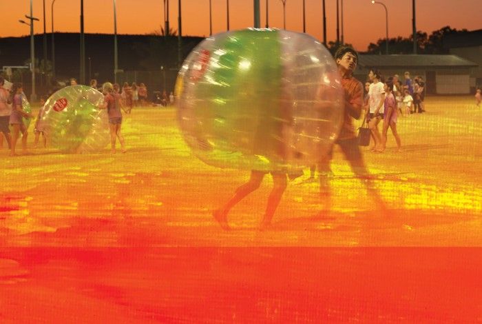 youth aged person inside a zorb ball with youth surrounded