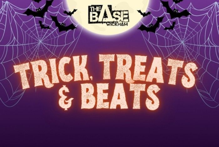 A Halloween-themed graphic with a purple background, spider webs in the corners, bats flying around a full moon, and “The BASE Wickham” logo at the top. Large bold text in the center reads: “TRICK, TREATS & BEATS.”