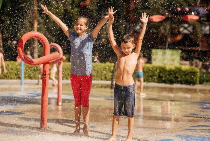Picture of two children enjoying waterplay area with arms up
