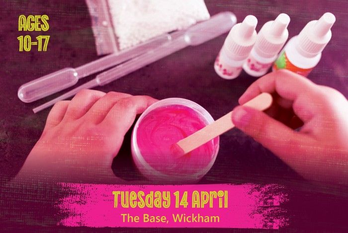 Hands mix bright pink slime in a small container using a wooden stick, with craft tools and small bottles nearby. A pink banner reads “Tuesday 14 April – The Base, Wickham,” and text on the left says “Ages 10–17.”