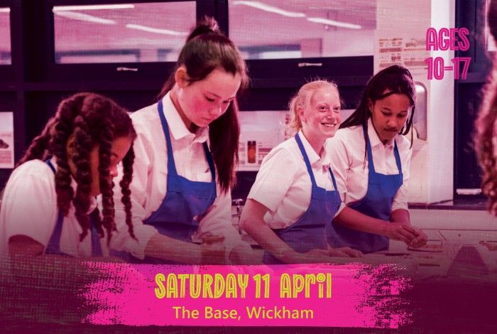 Four young people wearing blue aprons work together at a kitchen bench during a cooking activity. A pink banner reads “Saturday 11 April – The Base, Wickham,” and text on the right says “Ages 10–17